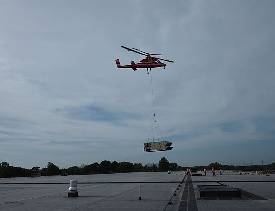 helicopter placing hvac unit on roof of building