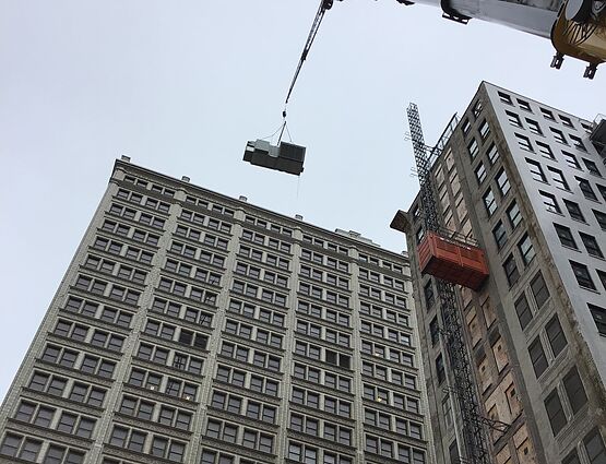 ground view of crane lifting hvac unit to roof