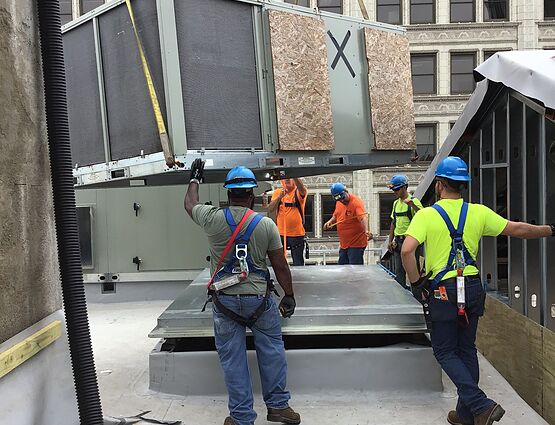 workers placing hvac unit on rooftop